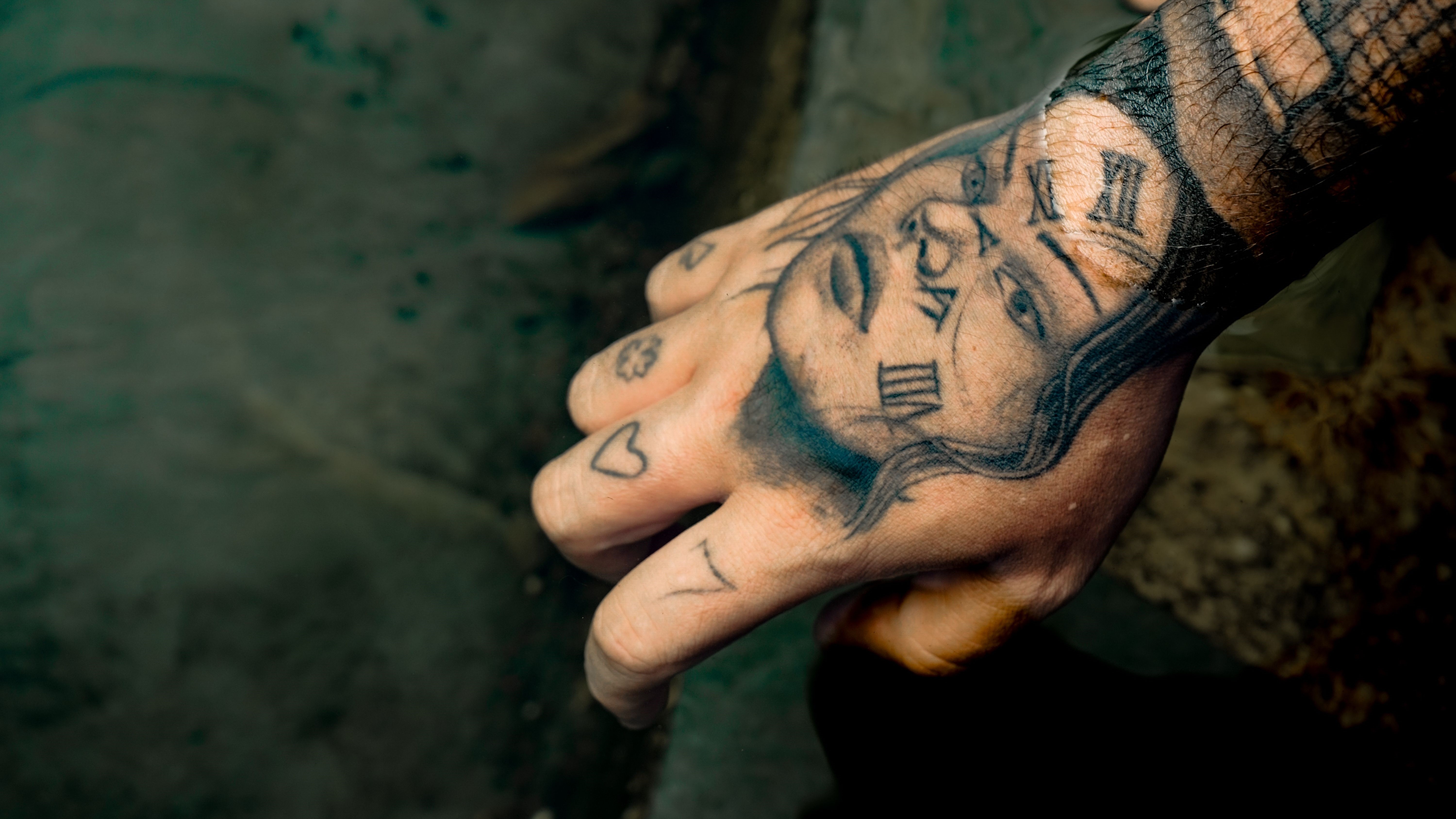Dorso da mão com realismo e numerais romanos em blackwork